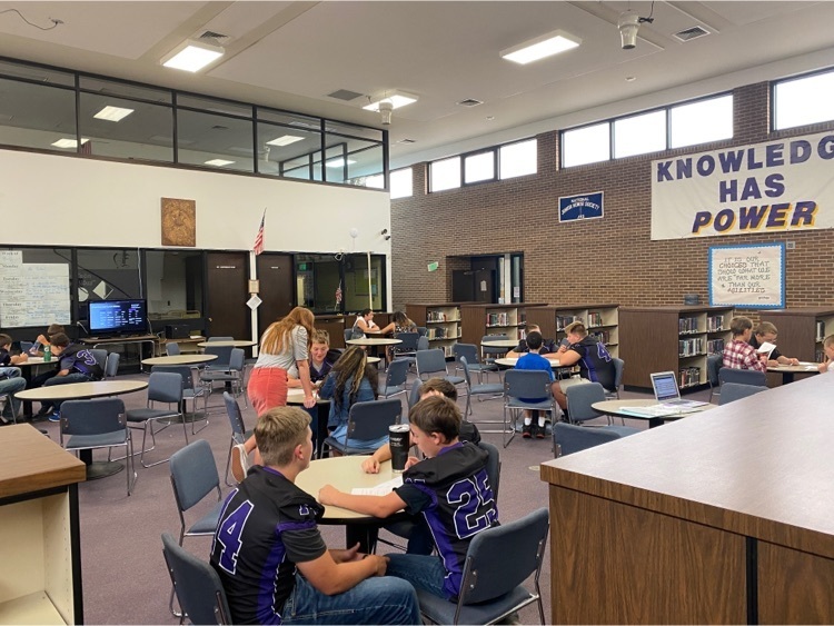 students gather around circle tables in the library