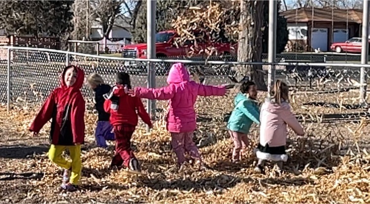 children playing in corn husk pile